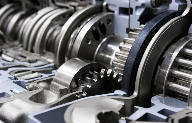 Metal gears interlock and rotate within a machinery assembly surrounded by intricate components inside an industrial setting.